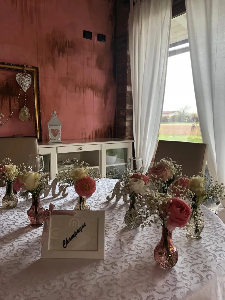 Il tavolo degli sposi con fiori rosa davanti al muro rosa della cascina